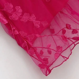 Détails de broderie sur tissu en maille fuchsia avec motifs floraux élégants