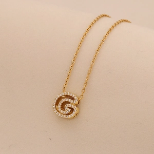 Detailed close-up of a gold-plated letter G pendant necklace with sparkling crystal inlay