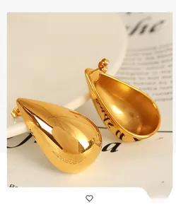 Detail shot of highly polished 18k gold plated teardrop stud earrings on white ceramic