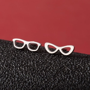 Detailed macro shot of asymmetrical silver eyeglass studs on a dark textured surface