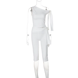 Detail of white two-piece set featuring a one-shoulder tie-up top and fitted capri pants