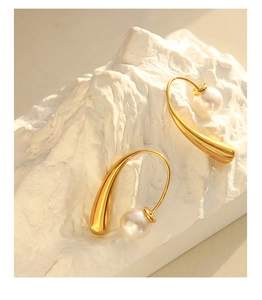 Detailed view of gold hooks with white round pearls on an elegant stone base