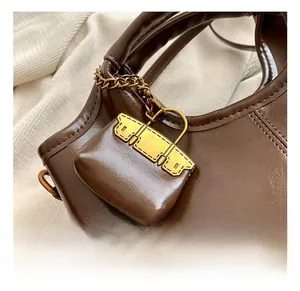 Detailed close-up of the vintage brown oil wax leather bag and the golden metal lock pendant