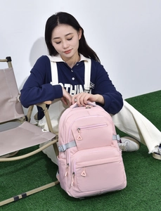 Outdoor shot of a pink student backpack with multiple zip layers on a lawn setting