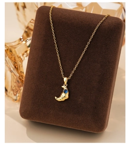 Macro detail of gold croissant pendant with blue gemstone on s925 silver necklace