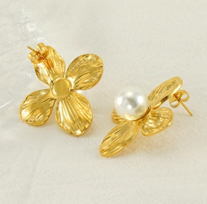 Detail of vintage gold flower petal earrings with pearl center on beige linen fabric