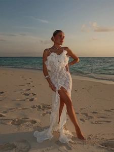 Gros plan sur la robe longue en dentelle blanche avec volants et fente haute à la jambe