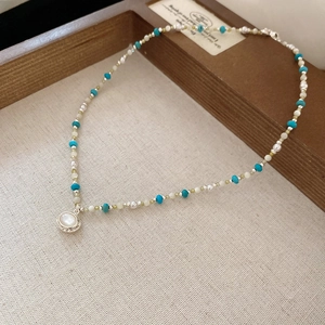 Dettaglio della collana di perline blu con ciondolo vintage in perla e madreperla