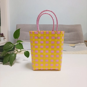 Detail of pink and yellow checkered woven tote bag with durable tube handles and metal rivets