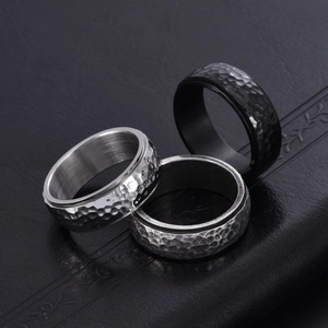 Three men's titanium steel spinner rings with hammered texture in black, silver, and grey