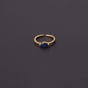 Detail of adjustable gold ring featuring a blue marquise zircon and beaded texture band