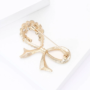 Detailed view of the gold bow brooch with intricate textured finish on a white stand
