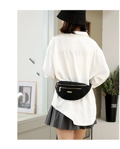 Back view of model wearing a black nylon waist bag with elegant gold zippers