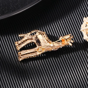 Golden giraffe brooch with crystal accents and secure back pin on a textured dark base