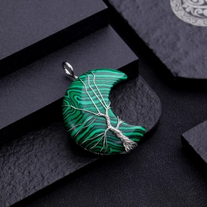 Close-up of malachite moon pendant with silver wire-wrapped tree of life on dark stone
