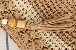 Détail d'un sac tissé main en corde de papier avec pompons, perles en bois et zip