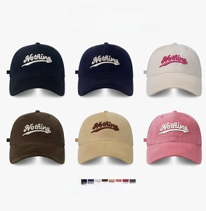 Close-up of embroidered 'Nothing' logo on a variety of cotton baseball caps in six colors