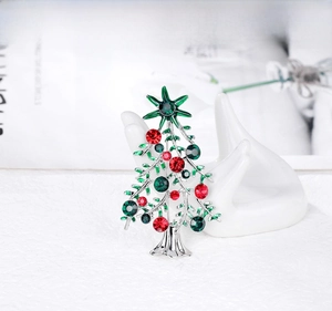 Detail of a silver Christmas tree brooch featuring sparkling red and green rhinestones