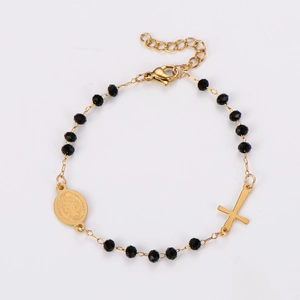 Detail of gold-plated stainless steel cross bracelet with black beads and religious medal