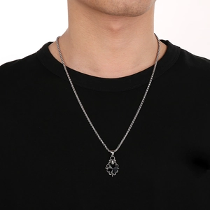 Close-up of vintage stainless steel cross pendant with black gemstone and floral engraving