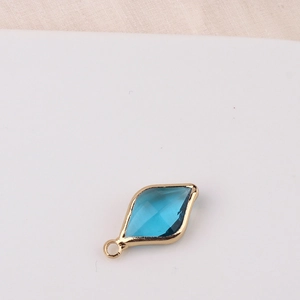 Detailed view of a blue rhombus crystal charm with golden copper frame for jewelry making
