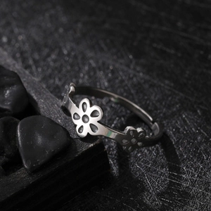 Polished stainless steel ring featuring three hollow flower motifs on dark textured background