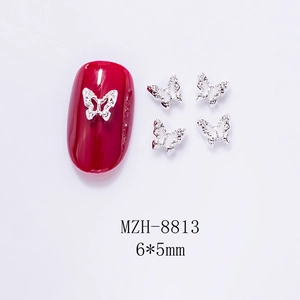 Macro view of 6x5mm silver hollow metal butterfly charm on red nail tip