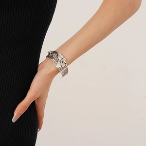 Detailed view of silver butterfly open bangle with intricate brushed metal texture