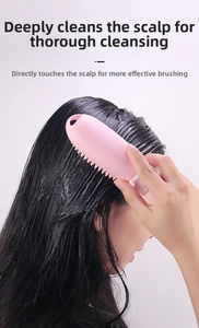 Pink silicone scalp massager brush with soft bristles being used on wet hair in detail