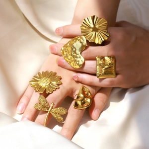 Close-up of stacked gold textured rings including heart and flower designs on silk