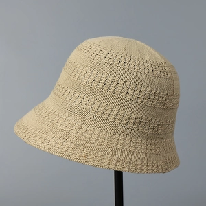 Close-up of beige knitted bucket hat featuring detailed hollow crochet patterns and texture