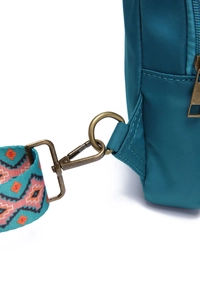 Detail of vintage bronze hook and geometric ethnic pattern woven strap on teal nylon bag