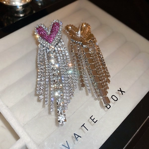 Detailed view of luxury heart tassel earrings with silver finish and rose red rhinestones