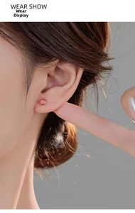 Close-up of a model wearing a brilliant orange round gemstone earring in a silver setting