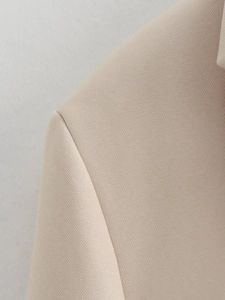 Detailed macro shot of beige twill fabric texture and precise stitching on a loose blazer