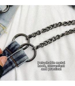 Detail of the detachable round hardware hook and chain on a studded denim shoulder bag