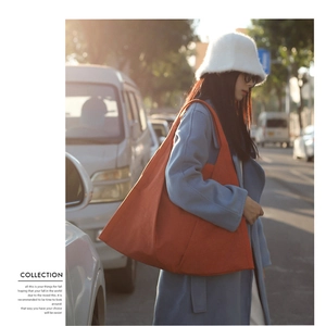 Close-up of a large orange canvas tote bag showing soft fabric and long shoulder strap