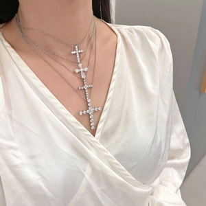 Detail of layered S925 sterling silver cross necklaces with zircon on white silk shirt