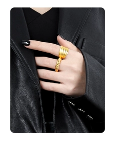 Close-up of golden twist rope ring and tiered wave design against black leather