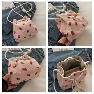 Dettaglio borsa a secchiello in velluto rosa con stampa di fragole e tracolla in corda bianca