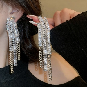 Gros plan de boucles d'oreilles pendantes élégantes avec cristaux étincelants sur mannequin