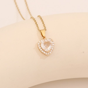 Golden heart necklace with micro-pave zircons and clear gemstone on a jewelry stand