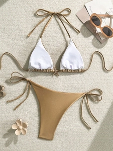 Detalle de bikini con adorno de estrella de mar dorada y lazos metalizados en tapete