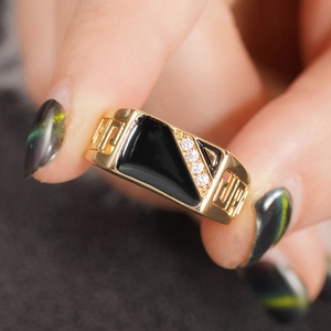 Macro detail of gold ring with black enamel, white zircons and Greek Key cutout design