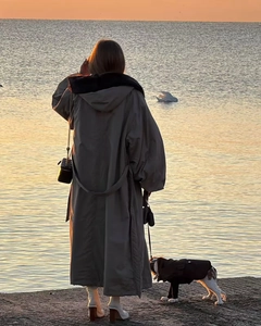 Vista posteriore di un parka invernale lungo grigio con cappuccio in pelliccia sul molo al tramonto