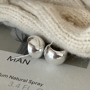 Macro shot of silver minimalist dome stud earrings with high-polish metallic finish