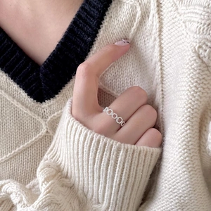 Close-up of minimalist 925 sterling silver hollow chain ring worn with a knit sweater