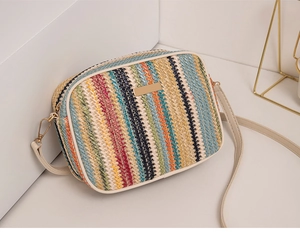 Macro detail of rainbow woven straw texture and cream faux leather trim on crossbody bag