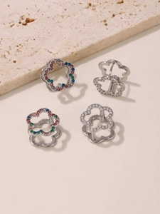 Detailed macro of flower-shaped huggie earrings featuring vibrant zircon stones and silver finish
