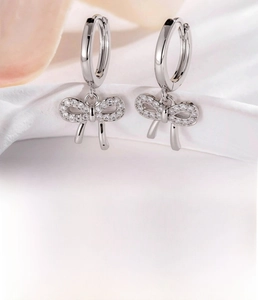 Détail de boucles d'oreilles nœud argentées avec zircons sertis et diamètre de 9 mm